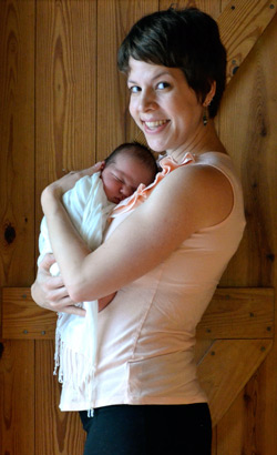 eine neue Mutter und ihr Baby vor eine Holztür.