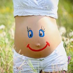 ein Smiley auf dem Bauch einer schwangeren Frau