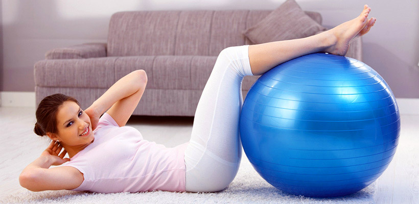 Eine Frau macht Gymnastik mit einem Fitness-Ball. 